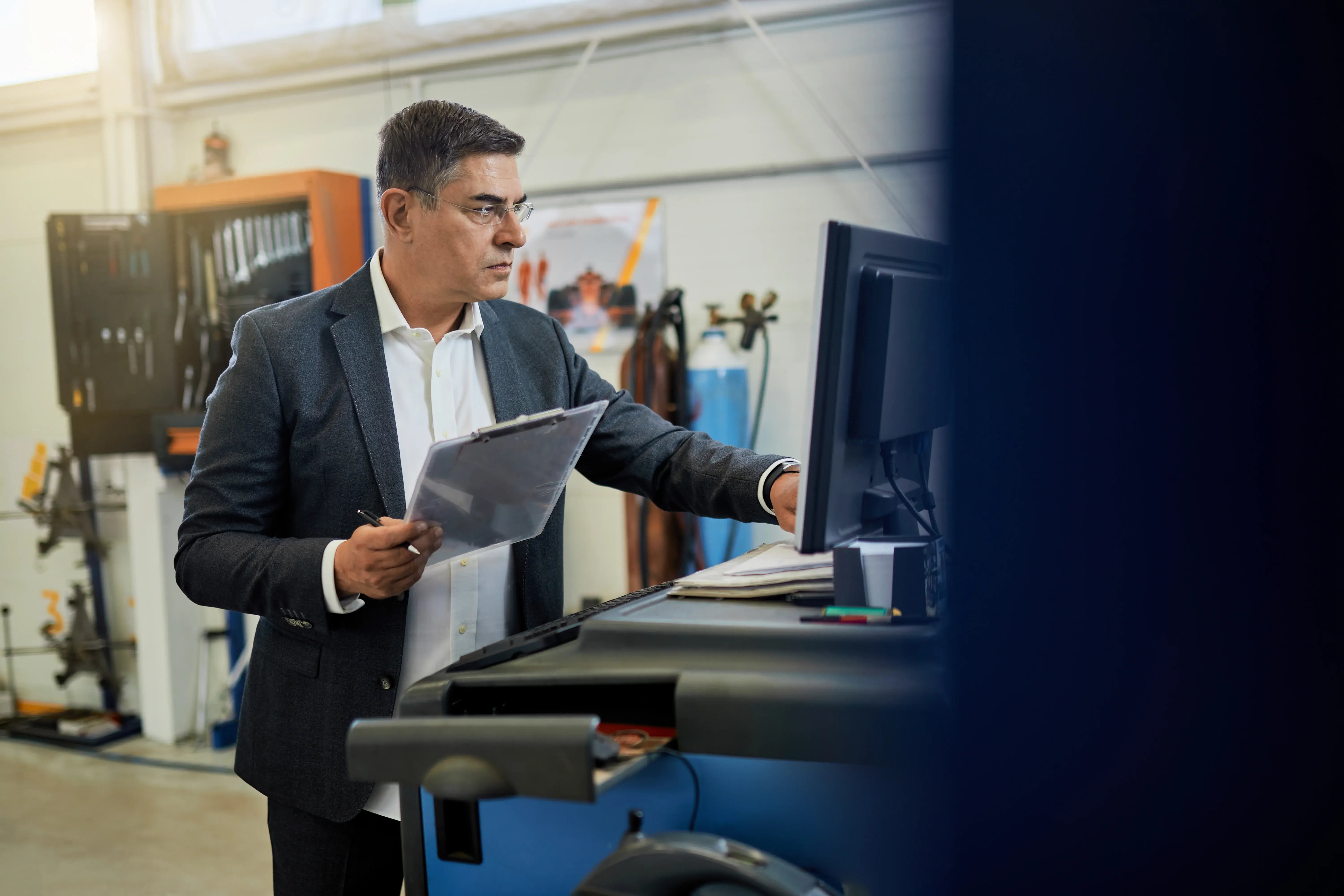 mid-adult-inspector-analyzing-data-while-using-computer-auto-repair-shop