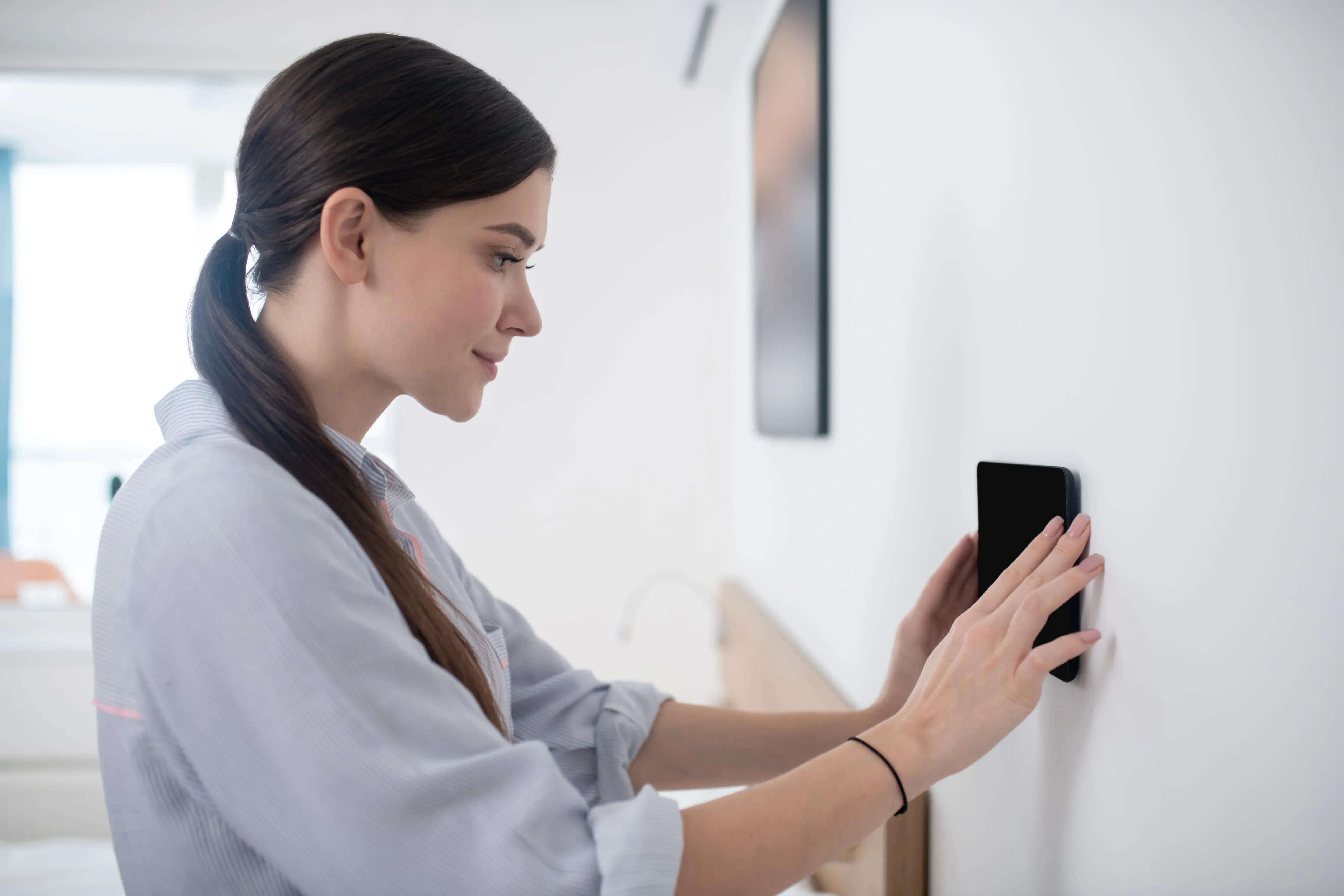 side-view-beautiful-young-woman-concentrated-attaching-tablet-wall